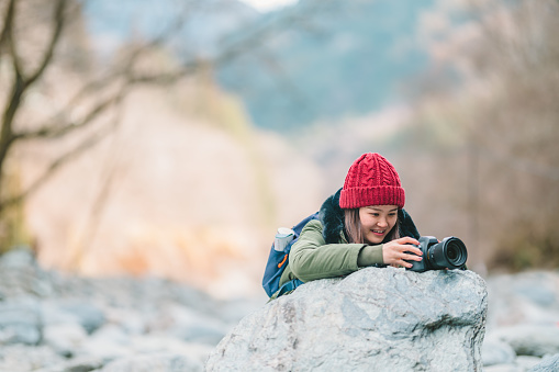 A young female tourist is taking photos of icy mountain in winter.