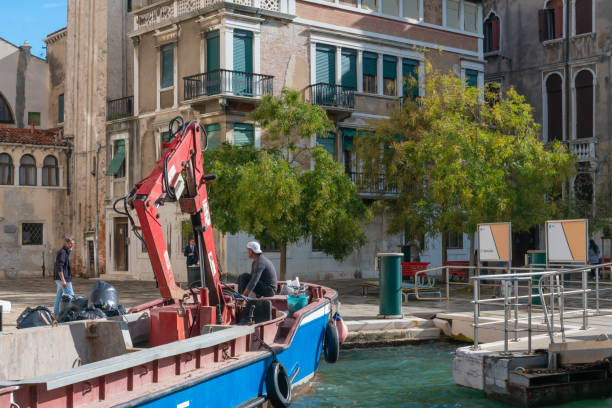 Venice canal  with a bridge in the foreground and parked moored boats and gondolas along the canalside.
