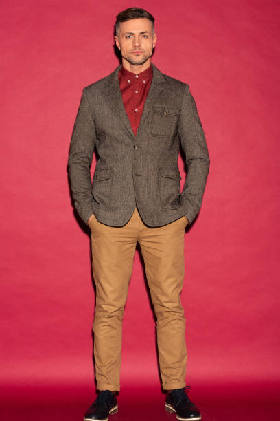 istock focused stylish man in formal wear looking at camera on red background 1124488478