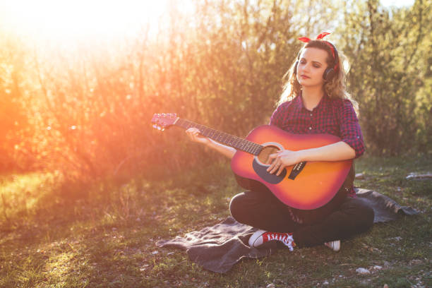 istock Woman play guitar by river 1124488895