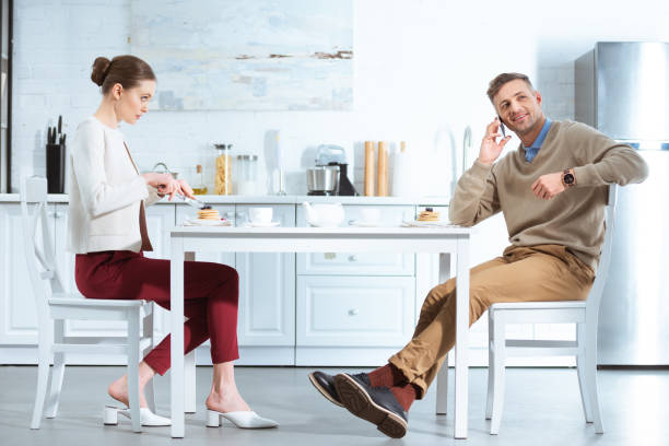 istock dissatisfied woman cutting pancakes while man talking on smartphone during breakfast in kitchen 1124491191