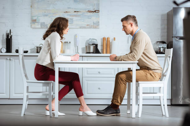 istock dissatisfied couple sitting with clenched fists at table in kitchen 1124491251