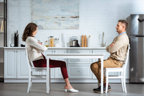 istock dissatisfied couple looking at each other while sitting with arms crossed at table in kitchen 1124491252