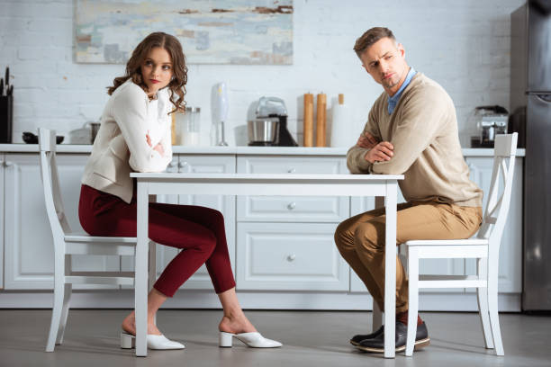 istock dissatisfied couple sitting with arms crossed at table in kitchen 1124491258