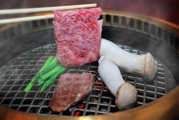 Japanese beef grill with chopstick in charcoal fire.
