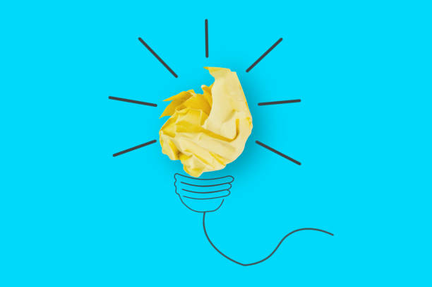 istock One crumpled yellow paper and image on blue table in office made light bulb. Top view. Inspiration concept 1124497532