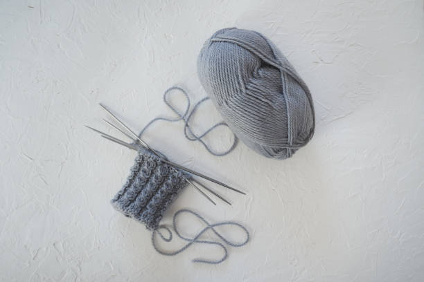 istock A ball of grey wool with knitting on a white table 1124500931
