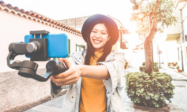 szczęśliwa azjatka vlogging ze statywem gimbal i smartphone - influencer chińska dziewczyna zabawy z nową technologią trendu - millennial generation działalności pracy, młodzieży i koncepcji technologii - skupić się na twarzy - happy kid audio zdjęcia i obrazy z banku zdjęć