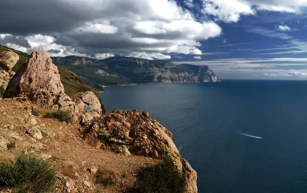 A traditional Ukrainian summer landscape in Crimea and blue sea and sky with clouds. The mountain slopes are covered with dry grass