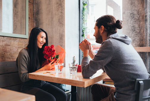 Young interracial couple on a date at the Bistro restaurant on Valentine's Day holiday.