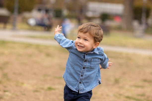 istock Cute boy in blue shirt running in the park 1124506302