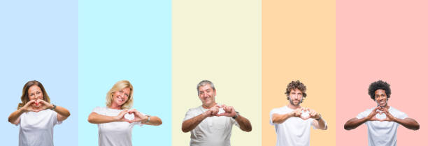 Collage of group of young and middle age people wearing white t-shirt over color isolated background smiling in love showing heart symbol and shape with hands. Romantic concept. Collage of group of young and middle age people wearing white t-shirt over color isolated background smiling in love showing heart symbol and shape with hands. Romantic concept. heart hands multicultural women stock pictures, royalty-free photos & images