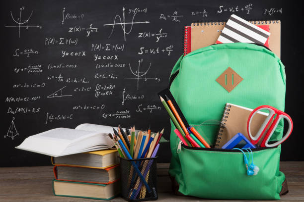 istock Education concept - school backpack with books and other supplies, blackboard background 1124513339