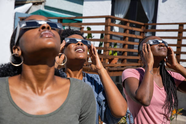 istock Women friends at home enjoying solar eclipse looking at the sun with eclipse sunglasses 1124521066