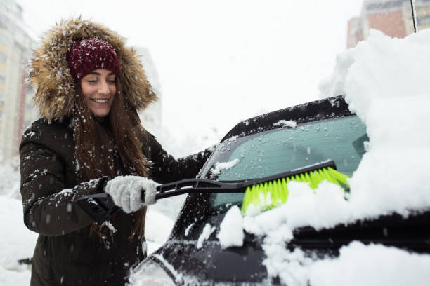 istock Young woman cleaning snow off her car 1124521406