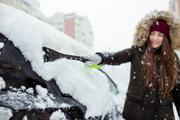 istock Young woman cleaning snow off her car 1124521526