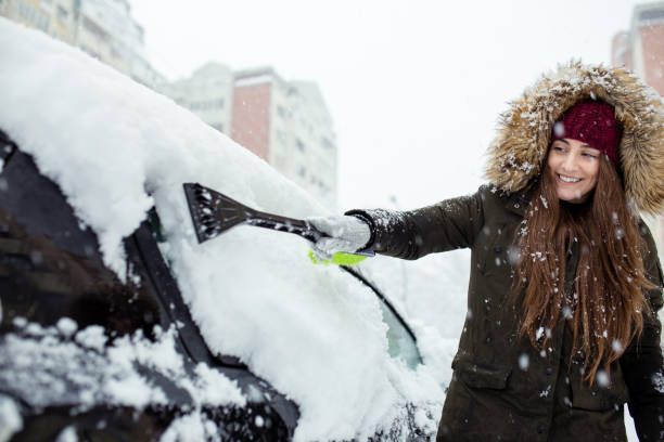 istock Young woman cleaning snow off her car 1124522050