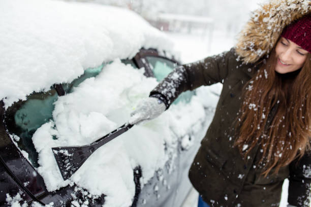 istock Young woman cleaning snow off her car 1124522061
