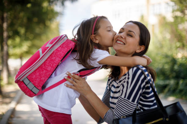 Daughter kissing mother in front of school Daughter kissing mother in front of school family with one child stock pictures, royalty-free photos & images