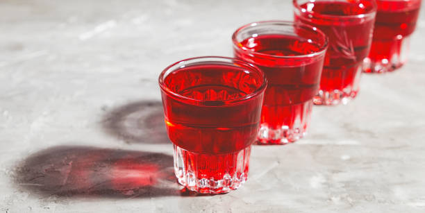 4 стакана с красной водкой на темном бетонном столе, вид спереди - kamikaze стоковые фото и изображения