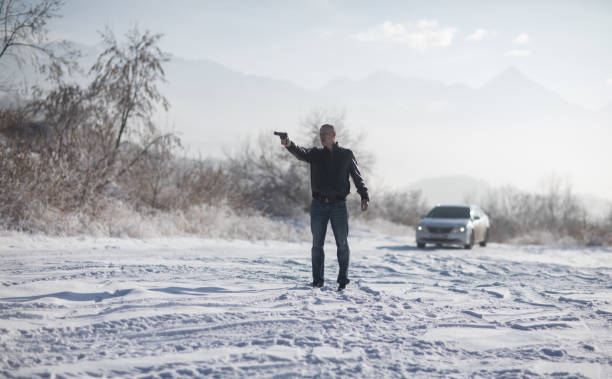 istock crime man with gun outdoors, winter 1124530010