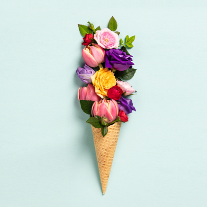 Ice cream cone with flowers and leaves. Summer minimal concept. Flat lay.