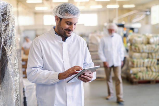 istock Close up of supervisor in uniform using tablet for checking data while standing in food factory. 1124532560