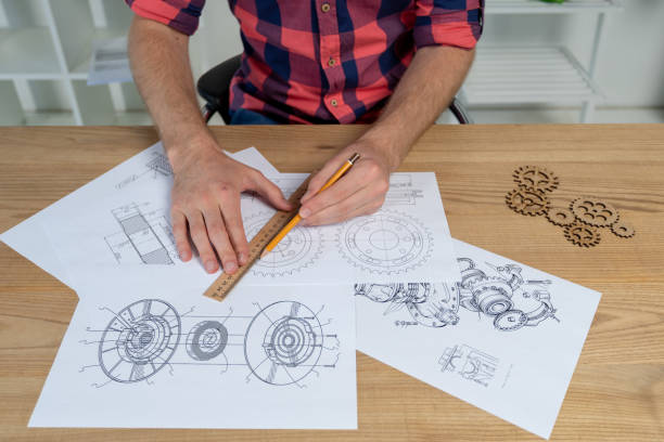 istock Man drawing gear wheel on paper using pencil and ruler 1124532811