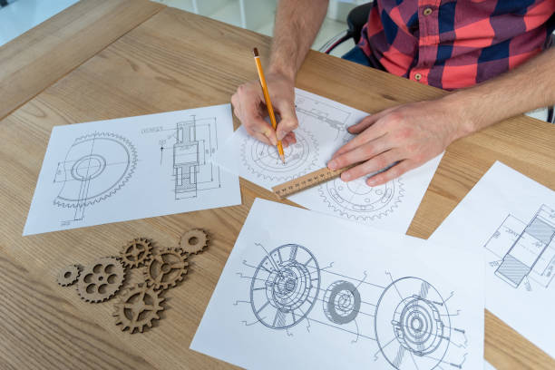 istock High angle and side top view of man making gear wheel drawing 1124532959
