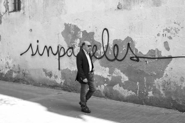 un lema que aparece en las paredes de barcelona: el graffiti "sinpapeles". - graffiti paintings men walking fotografías e imágenes de stock