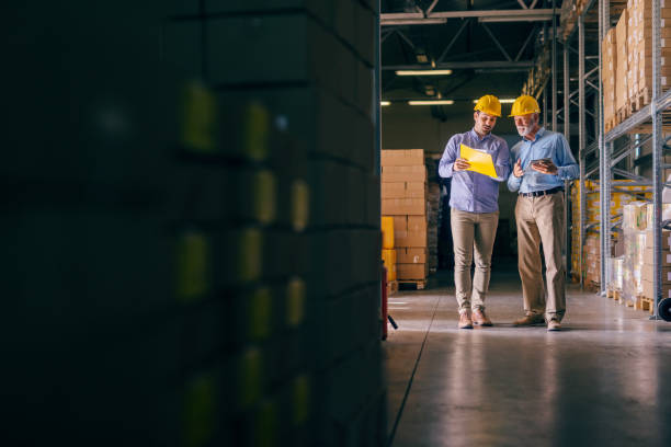 istock Two businessmen with helmets on heads discussing about shipping cargo. Storage interior. 1124534297