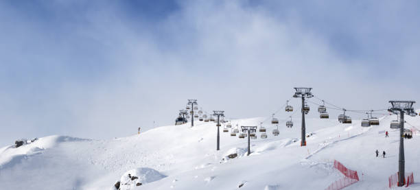 istock Panoramic view on snowy ski slope and ski-lift at sunny winter evening 1124536405