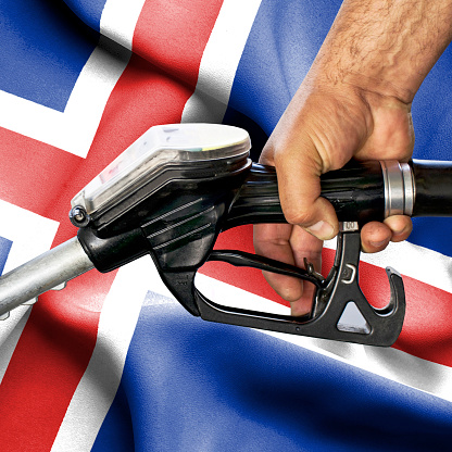 Gasoline consumption concept - Hand holding hose against flag of Iceland