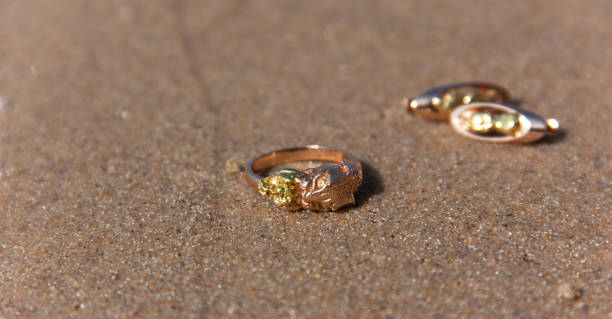 istock Gold jewelry thrown water on the sand 1124542900