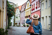 Woman wearing jeans jacket and straw hat is walking in ancient city Olomouc, Czech Republic.