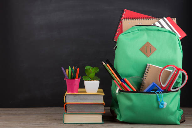 istock Education concept - school backpack with books and other supplies, blackboard background 1124546857