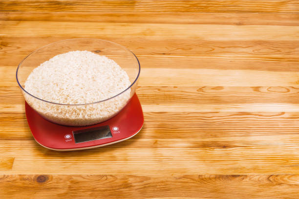 istock Rice in bowl on an electronic scale on a natural wood background with copy space 1124548796