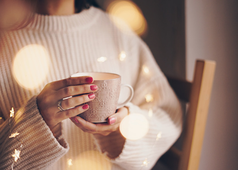 Woman in knitted sweater with a mug of coffee