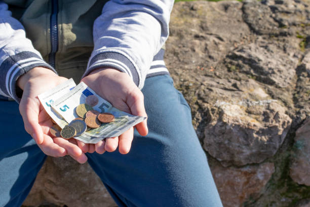 A child holds coins and euro notes in his hands. Pocket money image. A child holds coins and euro notes in his hands. Pocket money image. Poor low-income family, the concept of poverty, begging allowance stock pictures, royalty-free photos & images