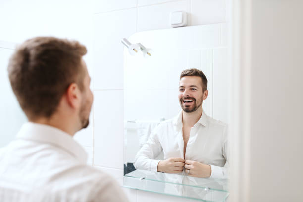 istock Smiling handsome businessman dressing up for work while standing in the bathroom in front of mirror. 1124556768