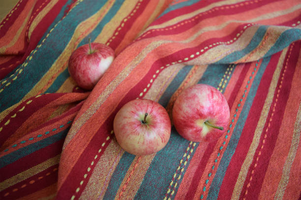 istock Three red apples on a folded striped warm-coloured fabric 1124561124
