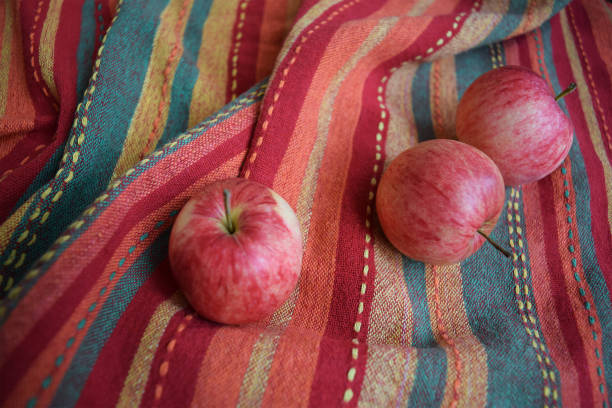 istock Three red apples on a folded striped warm-coloured fabric 1124561130