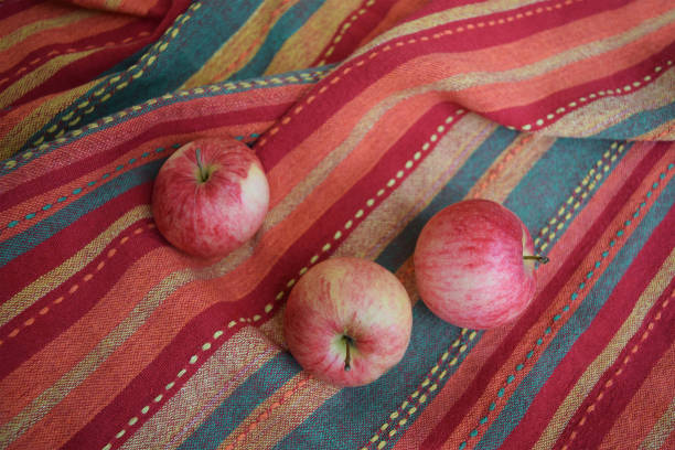 istock Three red apples on a folded striped warm-coloured fabric 1124561139
