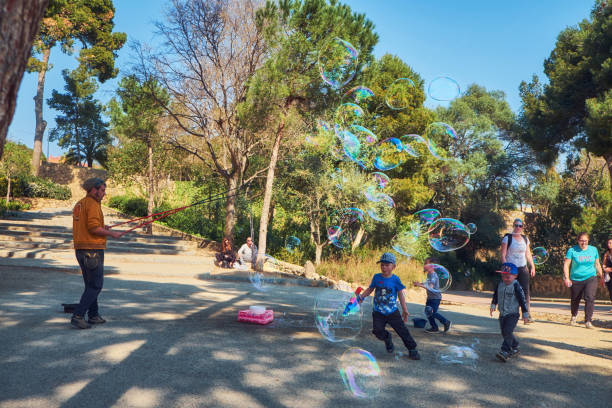 hombre soplando burbujas gigantes en el parque guel. calle actor inflando burbujas enormes para los niños. - balloon blowing inflating child fotografías e imágenes de stock