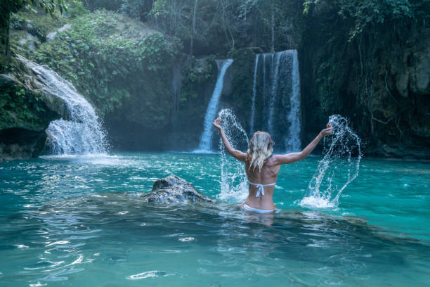 istock Young woman in waterfall playing with water 1124570479