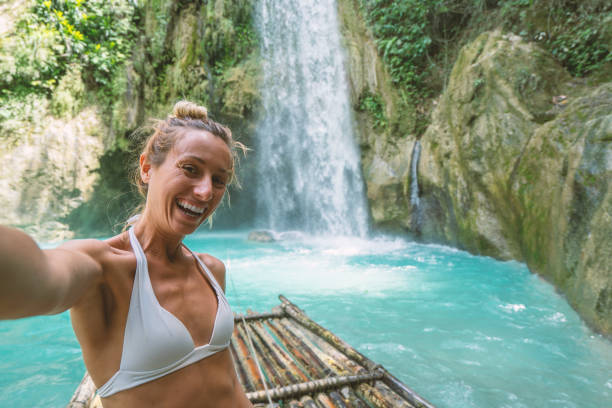 istock Beautiful young woman taking selfie at tropical waterfall 1124570814