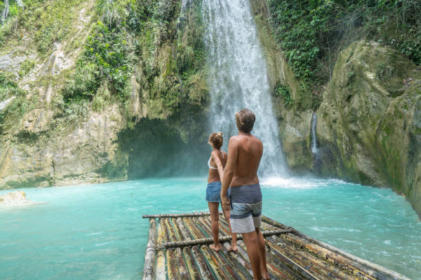istock Young couple contemplating beautiful tropical waterfall 1124570967