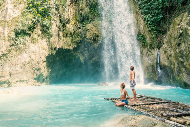 istock Young couple contemplating beautiful tropical waterfall 1124571004