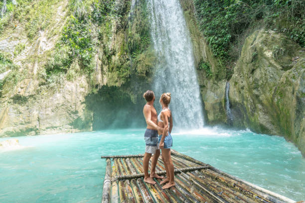 istock Young couple contemplating beautiful tropical waterfall 1124571554