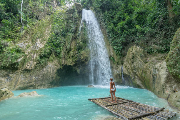 istock Young woman contemplating beautiful waterfall in tropical rainforest 1124572471